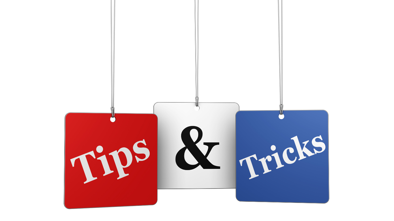 Three hanging signs with the words ‘Tips’ on a red background, ‘&’ on a white background, and ‘Tricks’