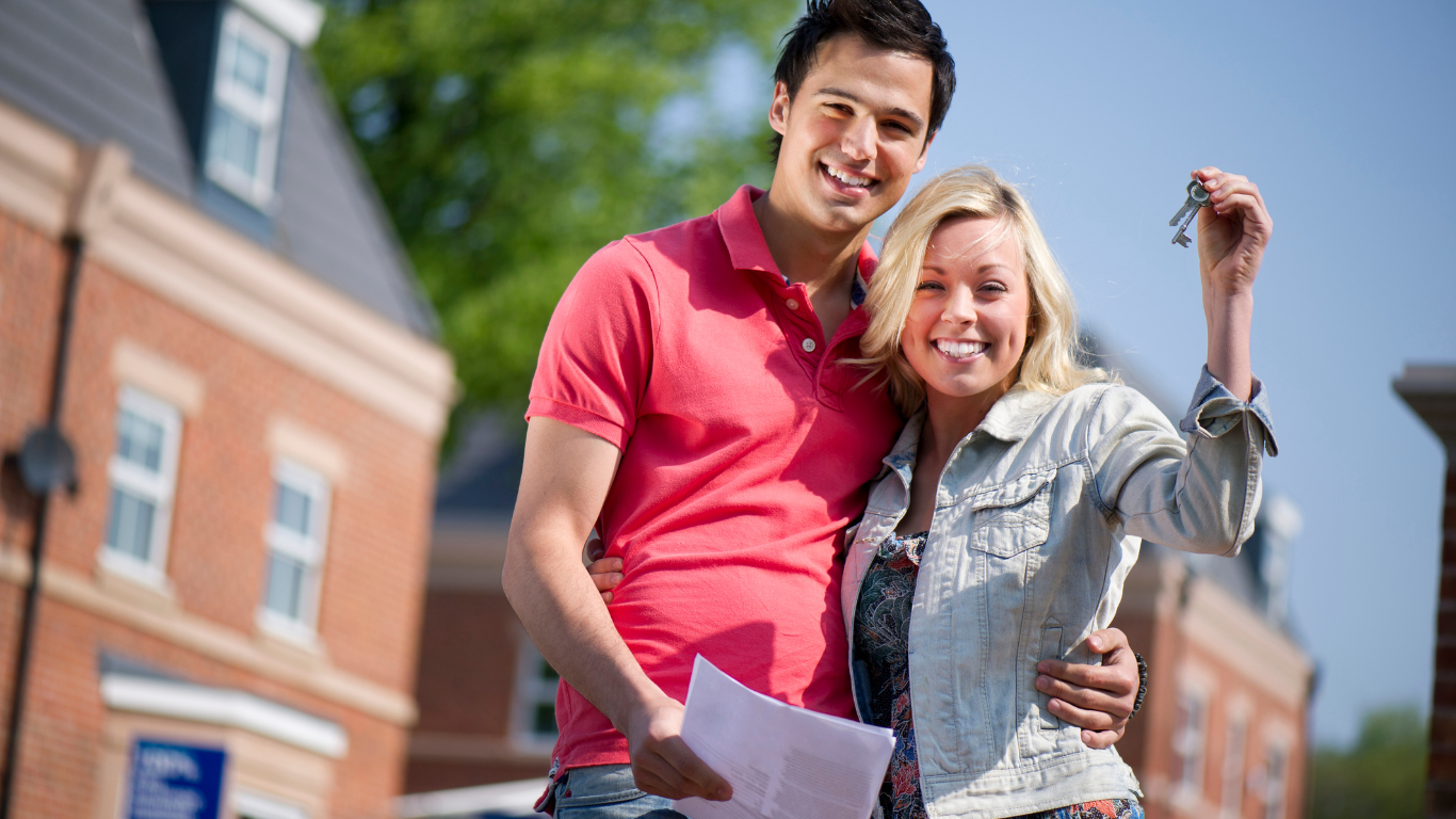 Steps to Buying Your First Home. Picture of First-Time Buyers holding the keys to their house.