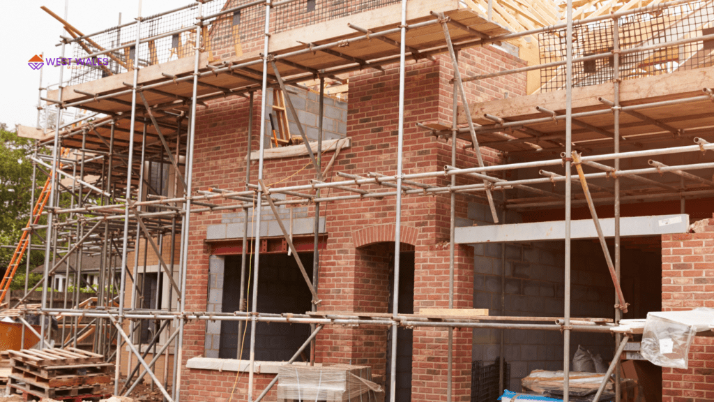 A brick building under construction with scaffolding surrounding it, and the text “SELF BUILDS” prominently displayed at the top