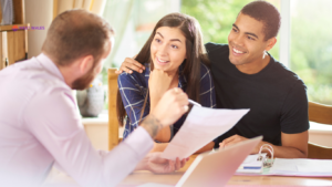 A couple receiving mortgage advice from an advisor in an office, smiling and reviewing documents together