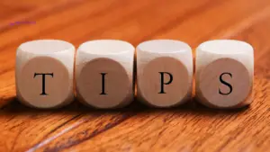 Wooden blocks spelling out the word 'TIPS' on a wooden surface, with the West Wales Money logo in the corner. This image represents advice and tips related to critical illness insurance,