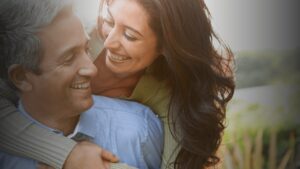 Happy couple over 50 smiling and embracing outdoors, symbolising financial security and the benefits of tailored mortgage solutions for later life