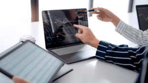 Understanding interest-only mortgages: Two professionals analysing financial charts on a laptop, discussing interest only mortgage options and repayment strategies