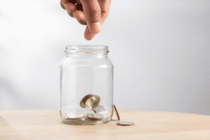 Hand dropping coins into a jar, symbolising how improving your Interest Coverage Ratio (ICR) can lead to financial growth and better mortgage terms