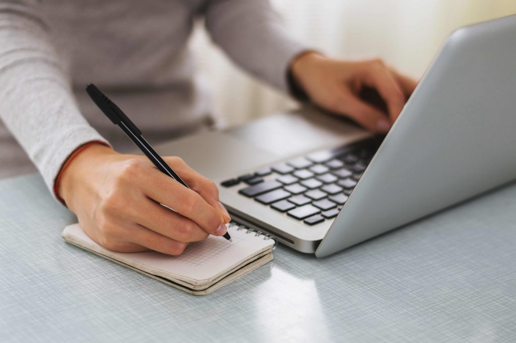 Person at their laptop writing down notes about the process of securing a mortgage for company directors.