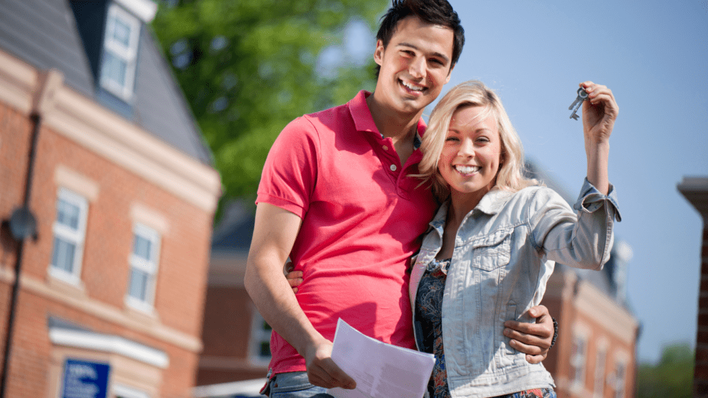 Steps to Buying Your First Home. Picture of First-Time Buyers holding the keys to their house.