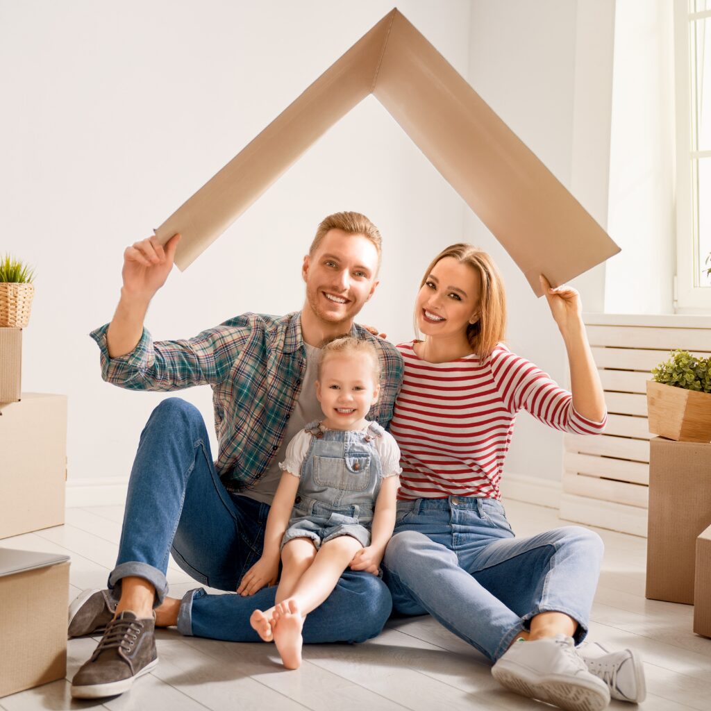 Young family sitting together under a cardboard roof symbol, highlighting the security of mortgage protection for safeguarding their home and future