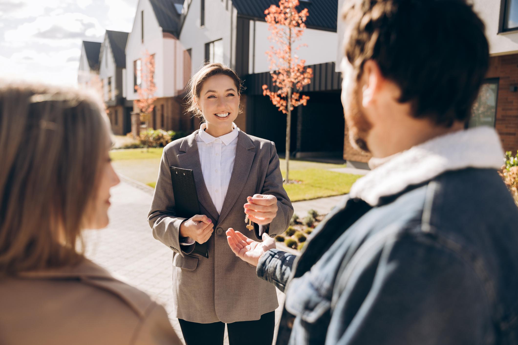 Confident smiling real estate agent handing over keys to new homeowners