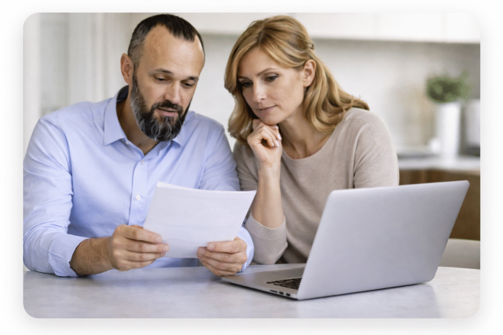 Couple in their fifties reviewing paperwork and laptop while planning an interest-only mortgage strategy