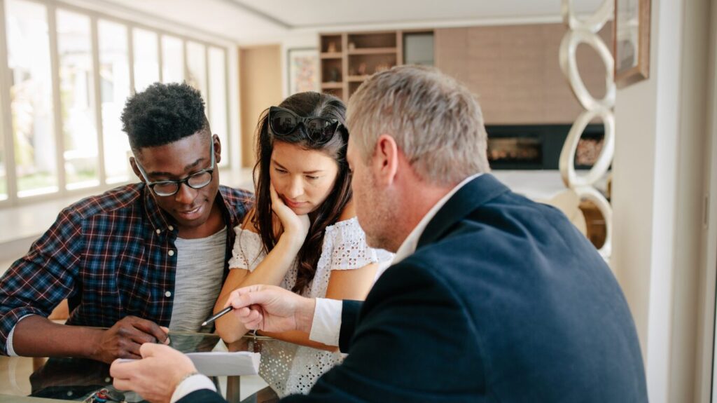 Mortgage adviser explaining guarantor mortgage options to first-time buyers during a consultation to help them secure their first home.