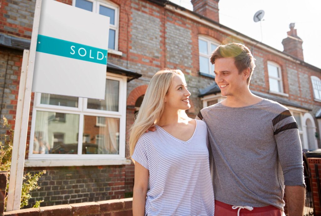 First-time buyers celebrating outside their new home after securing a guarantor mortgage
