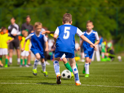 Children playing football during a youth match, highlighting the importance of protection against sports injuries for young athletes.
